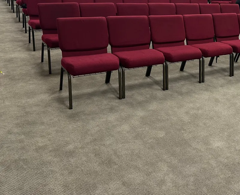 Red upholstered chairs in rows on a commercial carpet