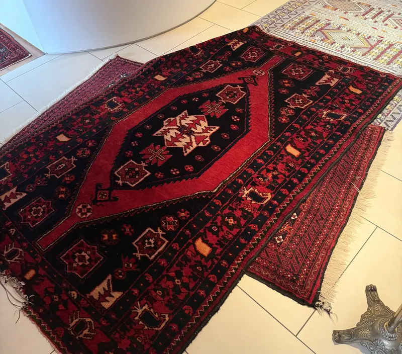 Red and black tribal pattern rugs laid on a tile floor
