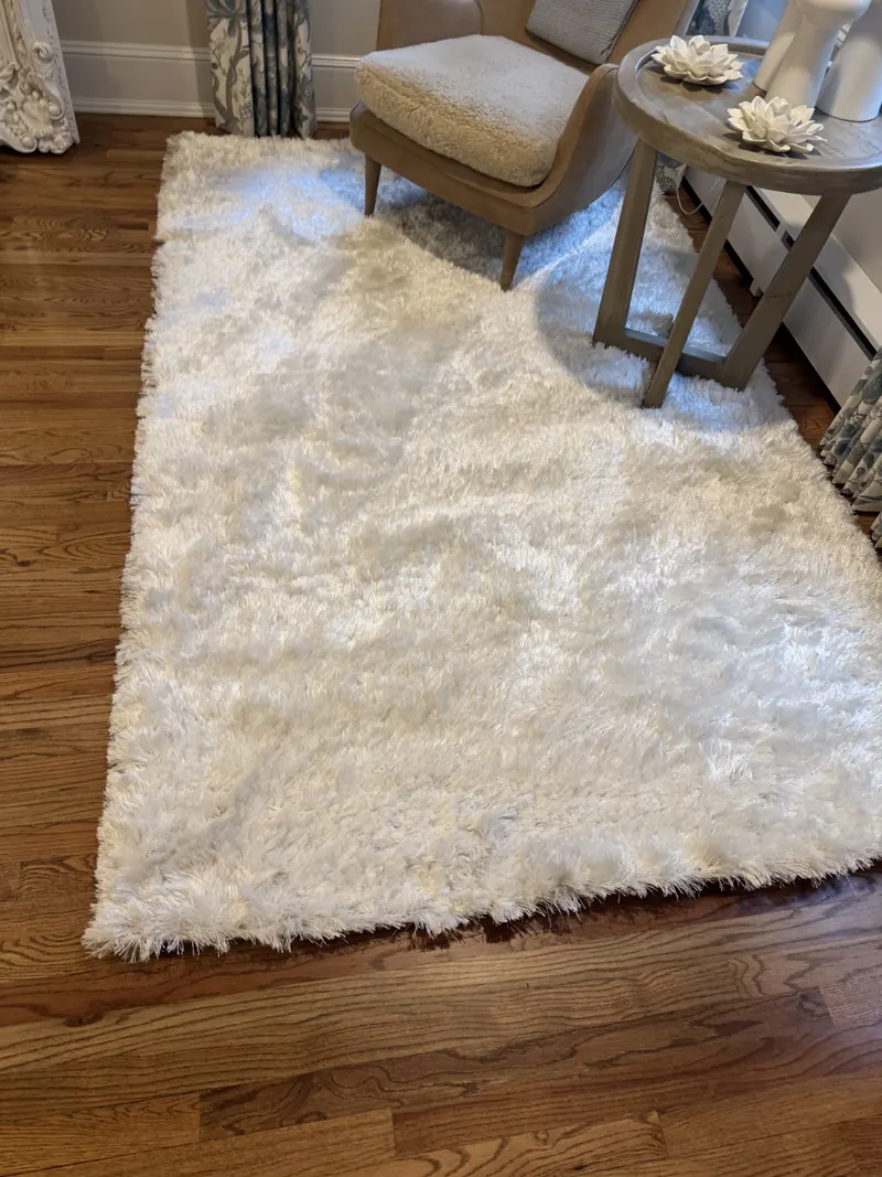 A white shag rug on a dark hardwood floor