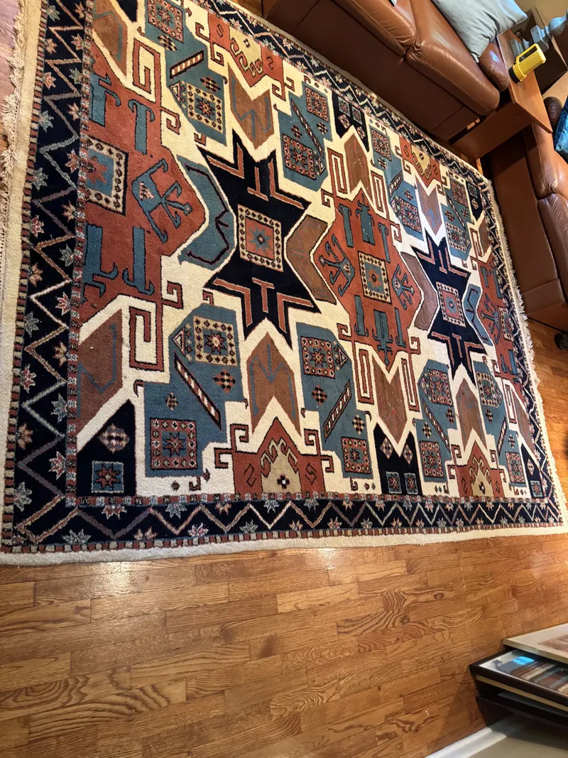 A geometric star pattern rug in rust, blue and ivory on a hardwood floor
