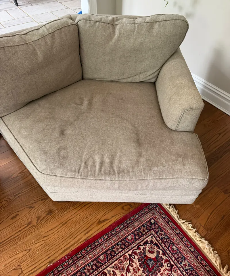 A beige fabric chaise with soil marks on the seat cushion